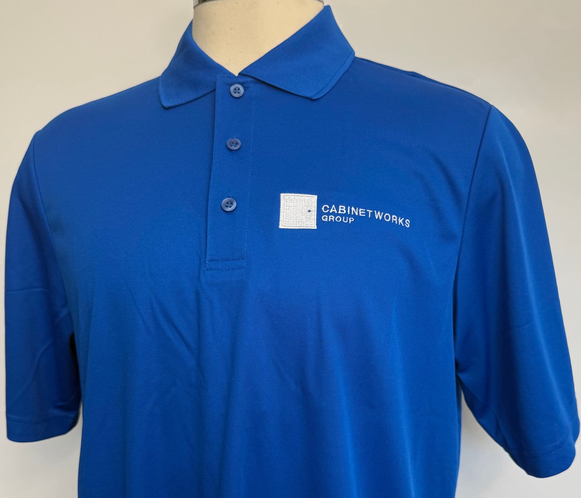 Royal blue polo embroidered with the white Cabinetworks Group logo