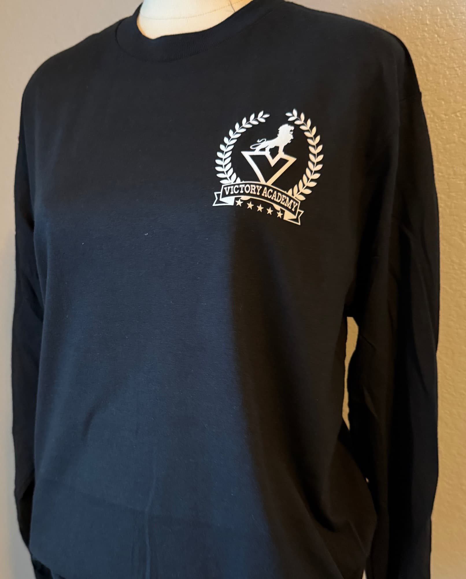 Black long-sleeve shirt printed with the white Victory Academy lion crest
