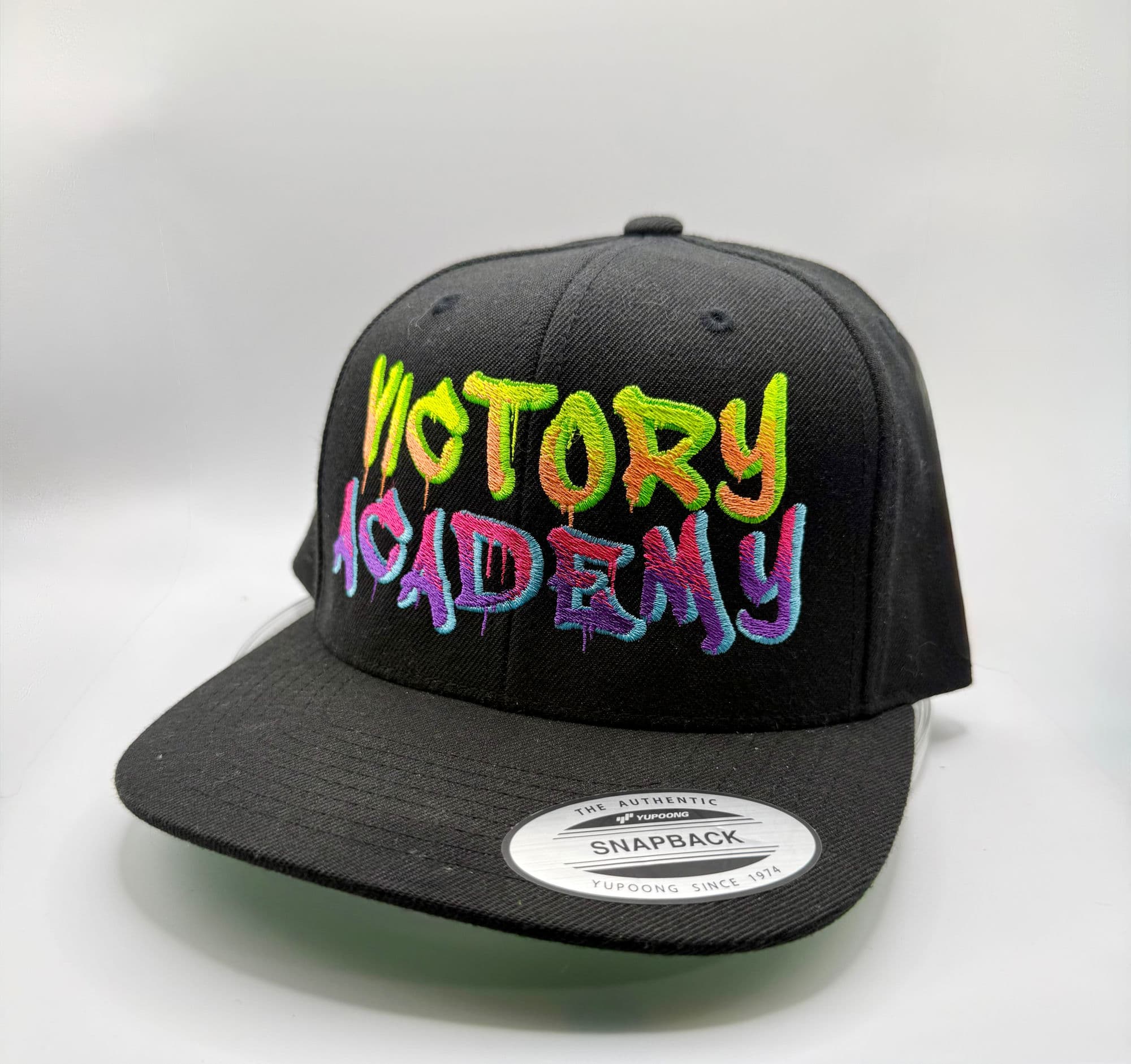 Black snapback hat with Victory Academy embroidered in multicolor graffiti-style lettering